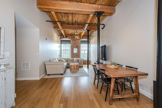 dining room with beam ceiling, light hardwood / wood-style flooring, and wooden ceiling