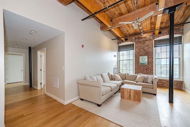 living room featuring wood ceiling, light hardwood / wood-style flooring, beamed ceiling, and brick wall