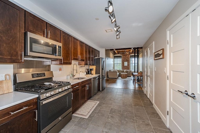 kitchen featuring dark brown cabinets, stainless steel appliances, track lighting, and sink