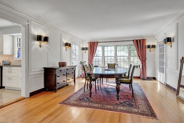 dining space with light wood-type flooring, plenty of natural light, and ornamental molding