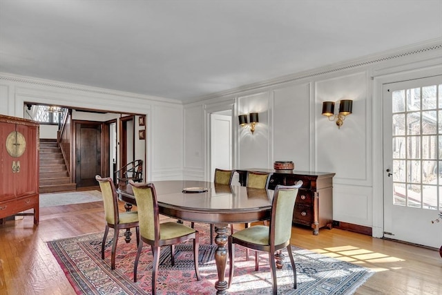 dining area featuring a healthy amount of sunlight, stairs, and a decorative wall