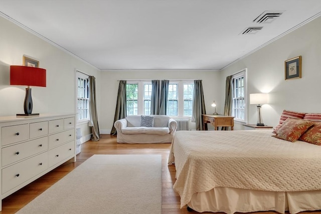 bedroom featuring visible vents, crown molding, radiator heating unit, and wood finished floors