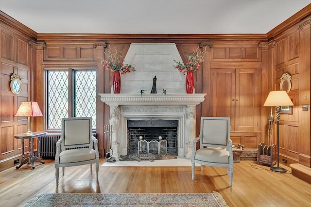 living area featuring a fireplace, wooden walls, radiator heating unit, and wood finished floors