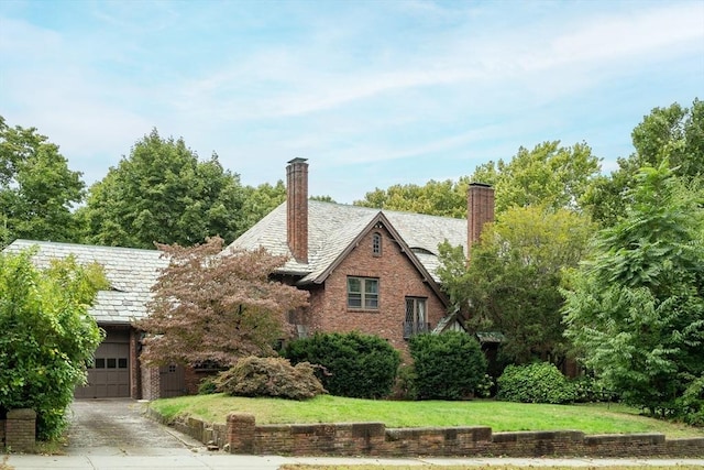 view of side of home with an attached garage, brick siding, concrete driveway, and a yard