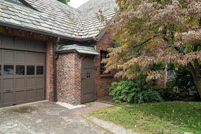 view of side of property featuring a garage, a high end roof, and brick siding