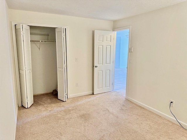 unfurnished bedroom featuring baseboards, carpet floors, and a closet