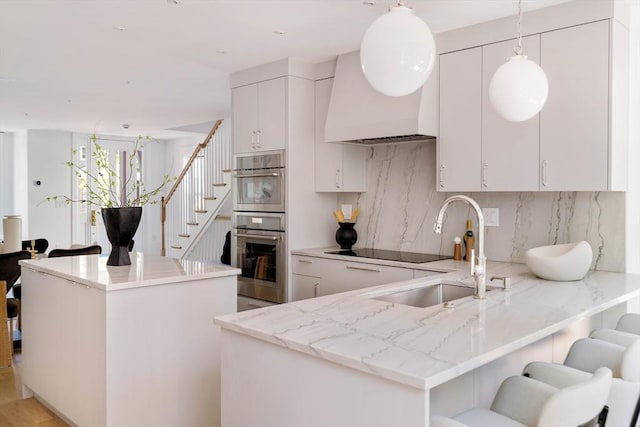 13 Mellen St Front, Front, Cambridge, MA 02138 - kitchen with a sink, stainless steel double oven, backsplash, a peninsula, and a center island