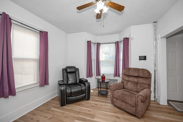 living area with light wood-type flooring, radiator, and ceiling fan