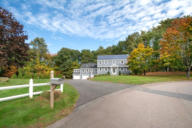 view of front of property featuring solar panels, a front lawn, and a garage