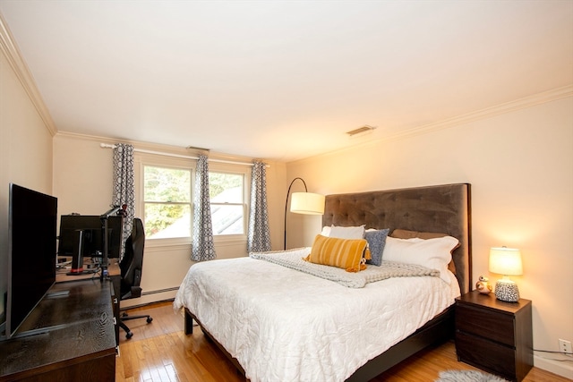 bedroom featuring hardwood / wood-style flooring, ornamental molding, and a baseboard heating unit