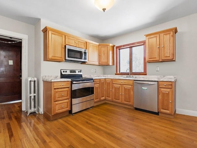 kitchen with a sink, radiator heating unit, dark wood-style flooring, and stainless steel appliances