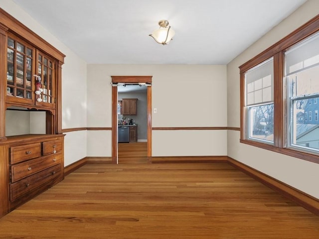 unfurnished dining area featuring light wood finished floors and baseboards