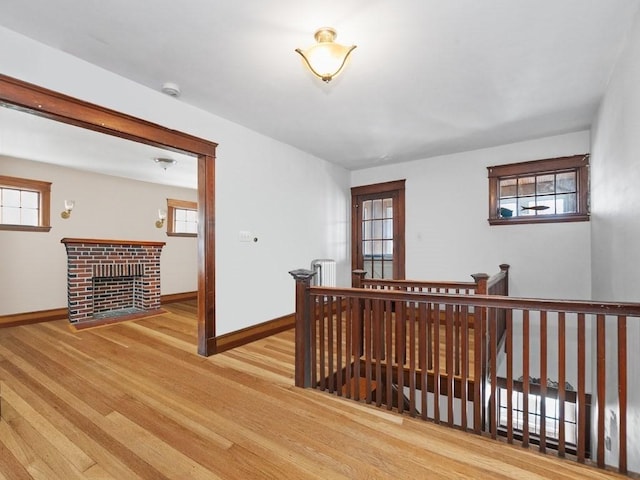 hall with baseboards, an upstairs landing, and wood finished floors