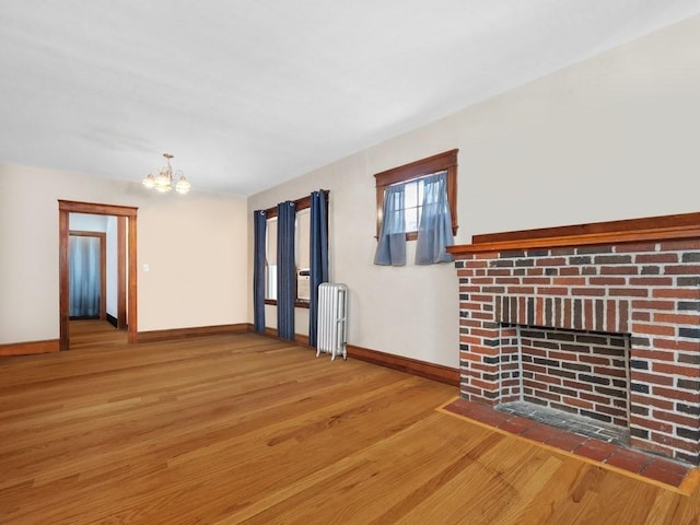 interior space featuring radiator, baseboards, a fireplace, an inviting chandelier, and wood finished floors