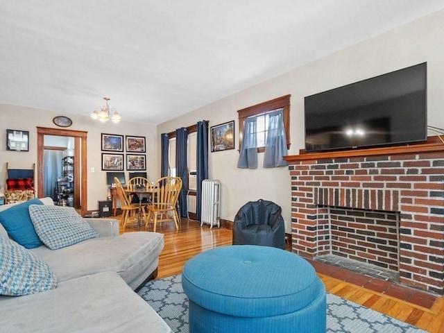 living area with baseboards, a chandelier, radiator heating unit, a fireplace, and wood finished floors