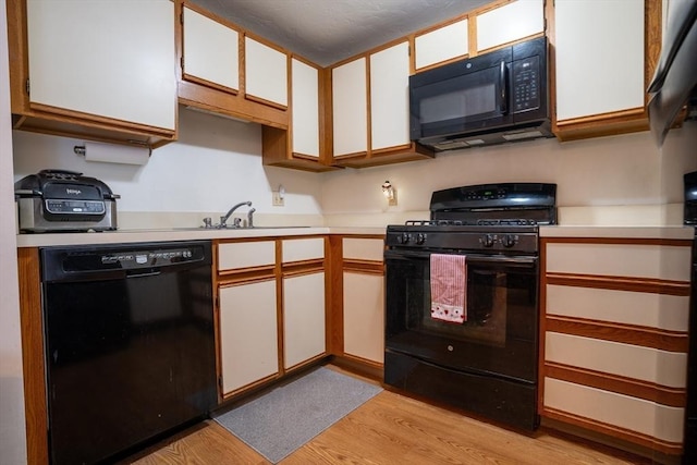 kitchen featuring sink, white cabinets, light hardwood / wood-style floors, and black appliances