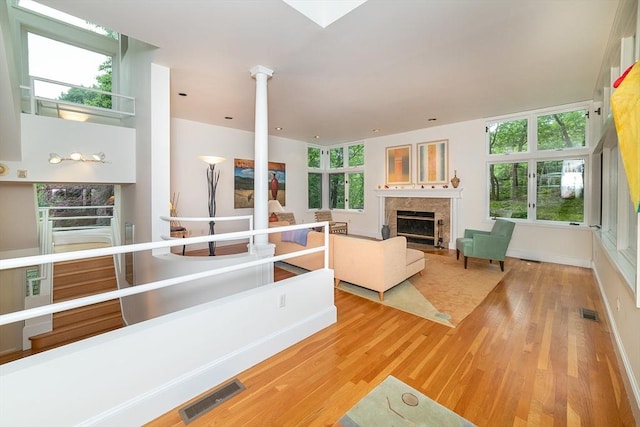 living room with visible vents, baseboards, wood finished floors, and a fireplace