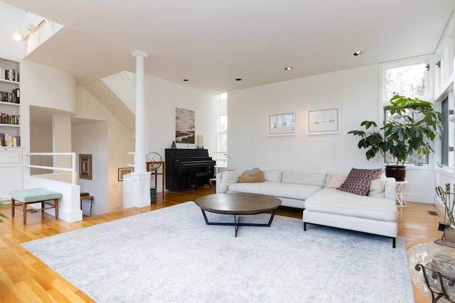 living room with visible vents, wood finished floors, and ornate columns