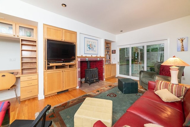 living room with light wood-type flooring, built in features, and a wood stove