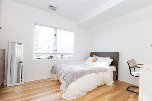bedroom with wood finished floors, baseboards, visible vents, and multiple windows