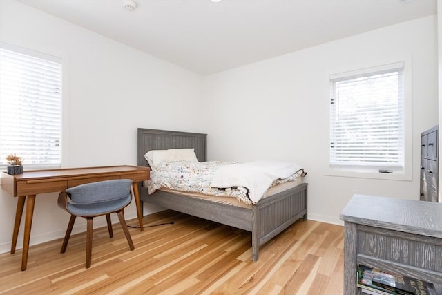 bedroom featuring baseboards, light wood-style flooring, and multiple windows