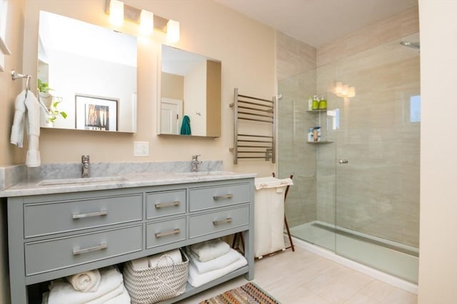 bathroom featuring a tile shower, double vanity, and a sink