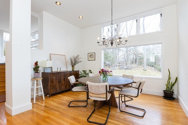 dining area with a towering ceiling, wood finished floors, a notable chandelier, and baseboards