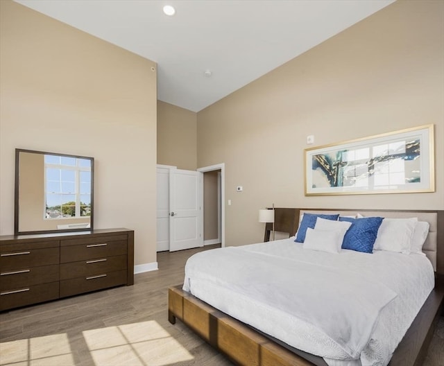 bedroom with light wood-type flooring and high vaulted ceiling