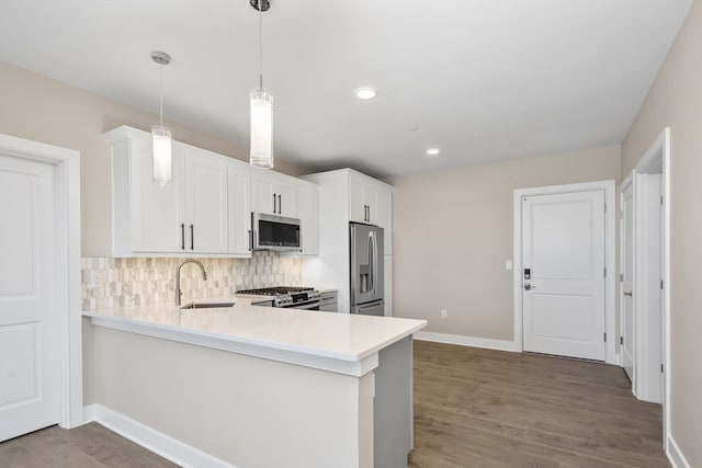 kitchen with light wood-type flooring, kitchen peninsula, appliances with stainless steel finishes, and sink