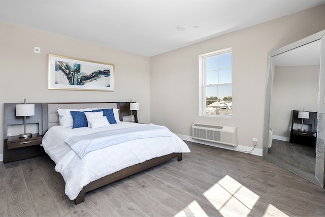 bedroom with hardwood / wood-style flooring and a wall mounted air conditioner