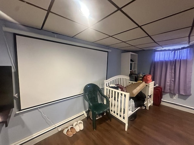 home theater room featuring a baseboard heating unit, a drop ceiling, and wood finished floors