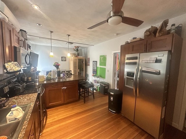 kitchen with ceiling fan, appliances with stainless steel finishes, a peninsula, light wood-style floors, and pendant lighting