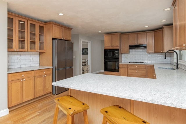 3 Integrity Way, Groton, MA 01450 - kitchen featuring black appliances, under cabinet range hood, a peninsula, decorative backsplash, and glass insert cabinets