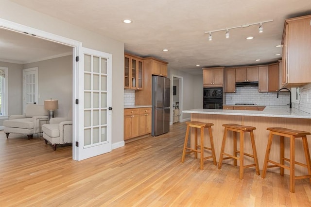 3 Integrity Way, Groton, MA 01450 - kitchen featuring black appliances, under cabinet range hood, a peninsula, backsplash, and light wood-style floors