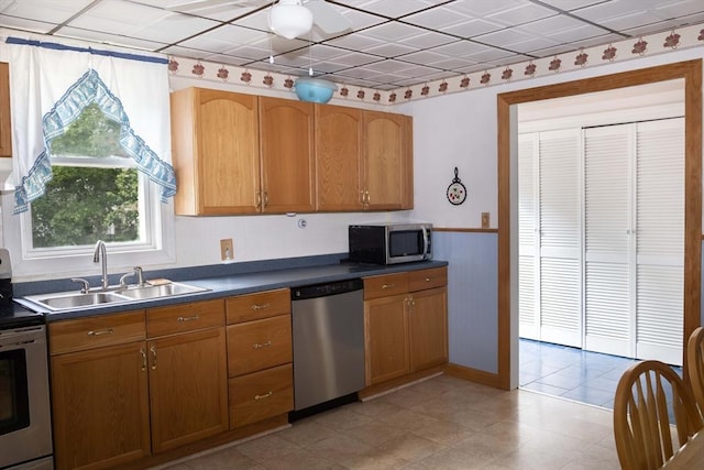 69 Front St, Shirley, MA 01464 - kitchen with appliances with stainless steel finishes, a sink, dark countertops, brown cabinetry, and a ceiling fan