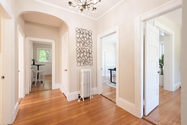 1690 Centre St Unit 2, Boston, MA 02132 - hall with radiator heating unit, arched walkways, light wood finished floors, a chandelier, and ornamental molding
