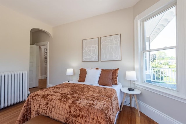 1690 Centre St Unit 2, Boston, MA 02132 - bedroom with radiator heating unit, wood finished floors, arched walkways, and baseboards