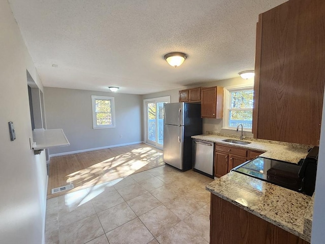 kitchen with a textured ceiling, plenty of natural light, sink, and stainless steel appliances