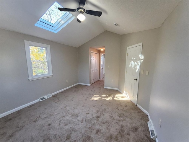 empty room with light colored carpet and lofted ceiling with skylight