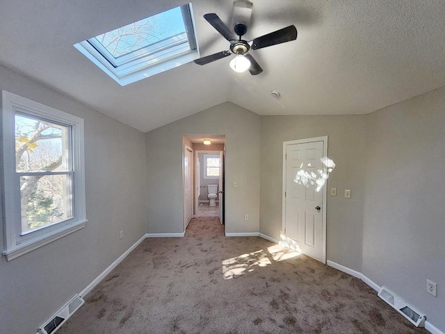 entryway with light carpet, vaulted ceiling with skylight, ceiling fan, and a healthy amount of sunlight