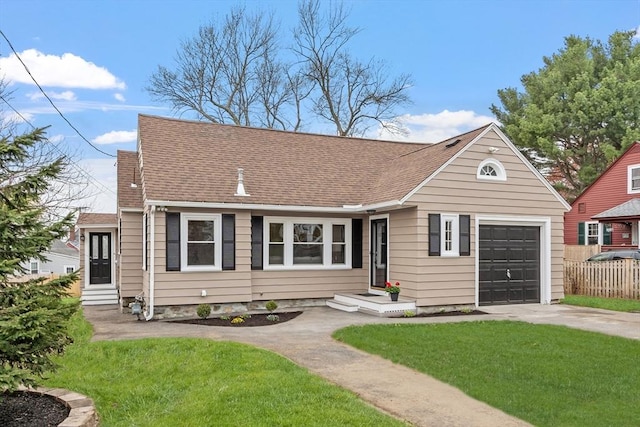 view of front of property with concrete driveway, fence, a shingled roof, and a front yard