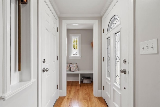 interior space featuring baseboards, ornamental molding, and light wood-style floors
