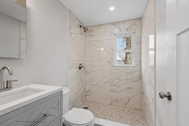 full bath featuring toilet, a tile shower, and vanity