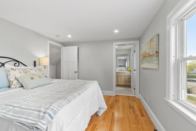 bedroom with baseboards, recessed lighting, a sink, light wood finished floors, and ensuite bath