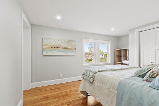 bedroom with baseboards, recessed lighting, light wood finished floors, and a closet