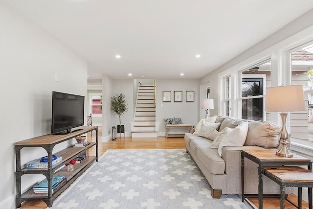 living room with recessed lighting, baseboards, light wood-type flooring, and stairs