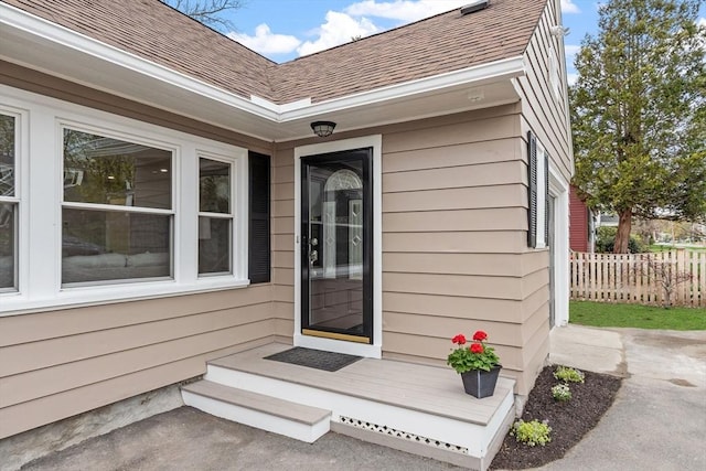 entrance to property with fence and a shingled roof