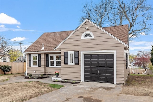 view of front of house featuring fence, concrete driveway, roof with shingles, and a garage