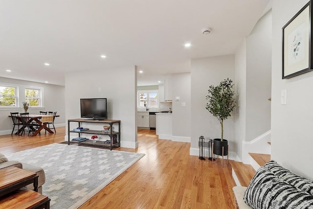 living area with a healthy amount of sunlight, recessed lighting, baseboards, and light wood-type flooring