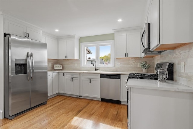 kitchen with a sink, stainless steel appliances, white cabinetry, and visible vents